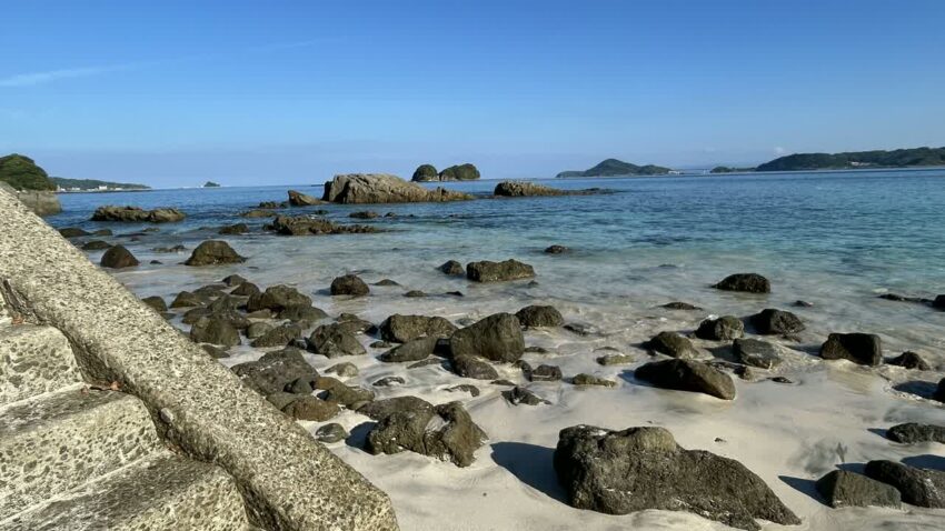 くじら浜の砂浜に続くコンクリート階段と岩場