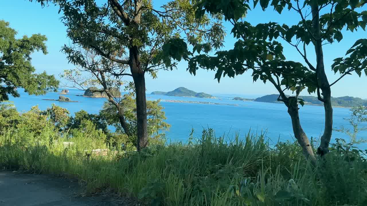 くじら浜へ向かう道の木々の間から見える青い海と沖の島々