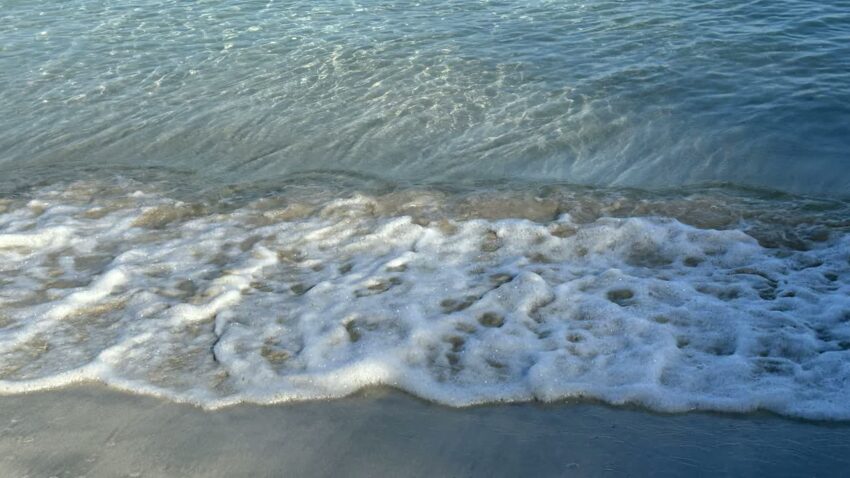 くじら浜の砂浜へ寄せる白い波と透けた海水